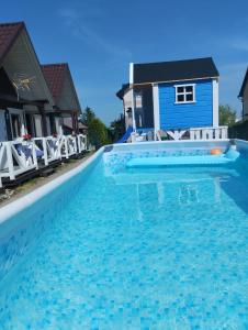 a swimming pool in front of a blue house at Domki letniskowe Na Stoku in Władysławowo