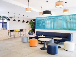 a lobby with tables and a couch and chairs at ibis budget Toulouse Colomiers in Colomiers