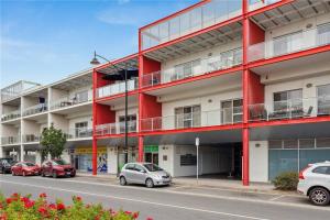 a red building with cars parked in front of it at Mawson Red - Free Pool access -Onsite Parking-Netflix-5 mins to Mawson Interchange in Mawson Lakes