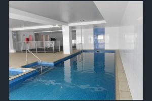 a large swimming pool with blue water in a building at Mawson Red - Free Pool access -Onsite Parking-Netflix-5 mins to Mawson Interchange in Mawson Lakes