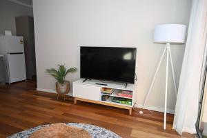 a living room with a flat screen tv on a white cabinet at Mawson Red - Free Pool access -Onsite Parking-Netflix-5 mins to Mawson Interchange in Mawson Lakes