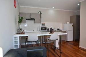 a kitchen with a white counter and chairs in it at Mawson Red - Free Pool access -Onsite Parking-Netflix-5 mins to Mawson Interchange in Mawson Lakes