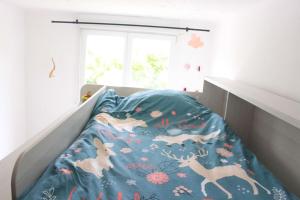 een bed met een blauw dekbed met dieren erop bij Maison et jardin à 5 min de Vannes in Meucon