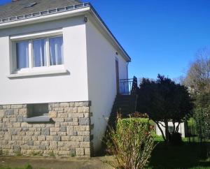 een wit huis met een raam en een bakstenen muur bij Maison et jardin à 5 min de Vannes in Meucon