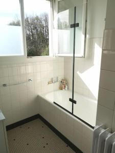 een witte badkamer met een bad en een raam bij Maison et jardin à 5 min de Vannes in Meucon