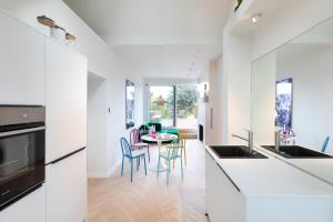 eine Küche mit weißen Arbeitsflächen und einem Tisch mit Stühlen in der Unterkunft HOMEFY - Luxury Art Apartment in Düsseldorf