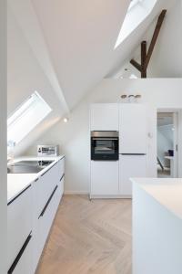 eine weiße Küche mit weißen Arbeitsflächen und Geräten in der Unterkunft HOMEFY - Luxury Art Apartment in Düsseldorf