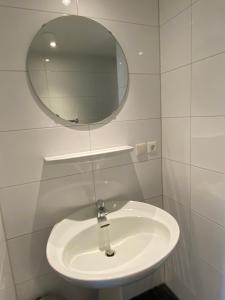 lavabo blanco en el baño con espejo en Bed and breakfast Carma Arnhem en Arnhem