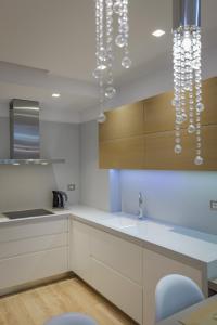 a kitchen with white cabinets and a chandelier at The View Luxury Apartment Center in Sarandë +45 photos