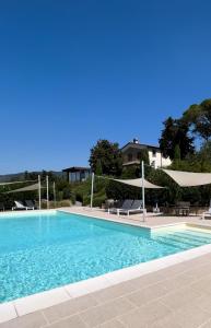 ein großer Pool mit Stühlen und Sonnenschirmen in der Unterkunft Agriturismo Casetta I in Vinci