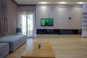 a living room with a bed and a tv on a wall at The View Luxury Apartment Center in Sarandë