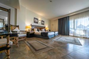 Jolie Ville Hotel & Spa Kings Island Luxor في الأقصر: غرفة نوم بسرير ومكتب واريكة
