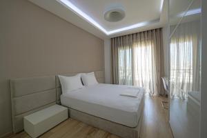 a white bedroom with a bed and a window at The View Luxury Apartment Center in Sarandë