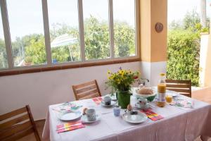 una mesa con un mantel blanco y flores en ella en Landhaus Casa Nonna im Olivenhain, en Balestrate