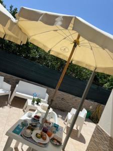a table with an umbrella and plates of food at Villa Dolce Vita rooms in Castelluzzo