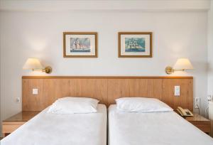 two beds in a room with two lamps and a phone at Danae Hotel in Egina
