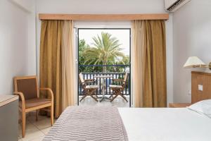 a bedroom with a bed and a balcony with a table and chairs at Danae Hotel in Egina