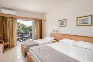 a hotel room with two beds and a balcony at Danae Hotel in Egina