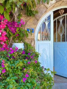 un edificio con una puerta azul y flores púrpuras en Dort Mevsim Alacati, en Alacati