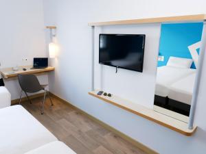Habitación con TV, cama y escritorio. en ibis budget Toulouse Colomiers en Colomiers
