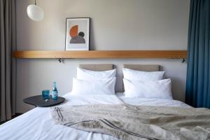 - un lit avec des draps blancs et une table dans l'établissement Val Blu Sport | Hotel | SPA, à Bludenz
