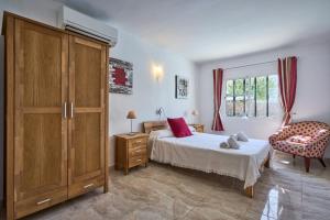 a bedroom with a bed and a cabinet and a chair at Villa Fleming in Santanyi +30 photos