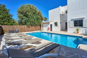 a pool with chaise lounge chairs and a house at Villa Fleming in Santanyi