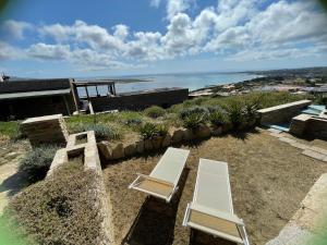 2 sedie bianche sedute su un patio con vista sull'oceano di Casa Capo Falcone - Terraced house with wonderful sea view - a Stintino