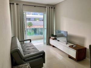 een woonkamer met een bank en een flatscreen-tv bij Residencial Amanda in Bombinhas