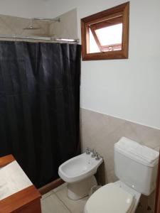 a bathroom with a toilet and a black shower curtain at Urban Hotel in Federación