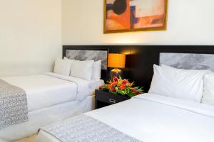 2 camas en una habitación de hotel con flores en una mesa en KC Hotel San Jose, en San José