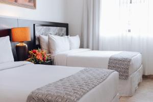 una habitación de hotel con 2 camas y una lámpara en KC Hotel San Jose, en San José