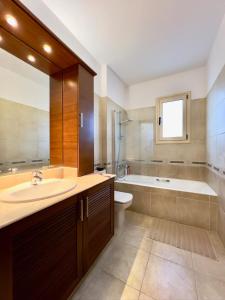 Paphos的住宿－Coral Azure，一间带水槽、浴缸和卫生间的浴室