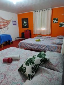 2 łóżka w pokoju z pomarańczowymi ścianami w obiekcie Perto Do Aeroporto De Salvador - Dona Pitanga Hostel w mieście Lauro de Freitas