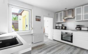 a kitchen with white cabinets and a window at Villa Helga- Fewo Morgensonne mit Terrasse, Kamin und 2 Schlafzimmer in Zinnowitz