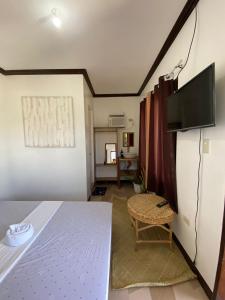 a room with a bed and a flat screen tv at SHELVES SIARGAO in General Luna