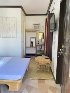 Zimmer mit einem Bett, einem Tisch und einem TV in der Unterkunft SHELVES SIARGAO in General Luna