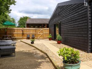 a backyard with a black house and a patio at The Goose Shed in Canterbury