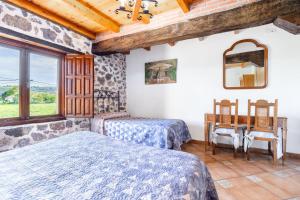 a bedroom with two beds and a table and a window at Casa Trasmiera in Solórzano