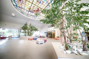 a large lobby with a stained glass ceiling and trees at Ohtels Vil·la Romana in Salou