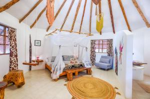 a bedroom with a canopy bed and a blue chair at Villa Morena Boutique Hotel Ecoliving in Akumal