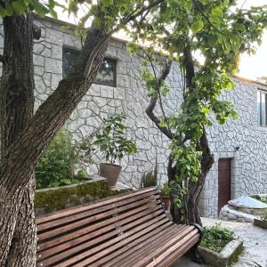 a wooden bench sitting in front of a stone building at Танхаус in Dilijan +17 photos