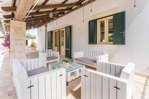 a patio with white chairs and a table at Villa Poggio Verde with pool - Exclusive Retreat in Noicattaro