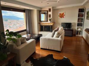 a living room with two white chairs and a fireplace at sunlight loft in Kastoria
