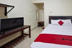 una camera da letto con un letto e una TV a schermo piatto di Reddoorz at Griya Kampar Madiun a Madiun