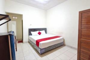 una camera da letto con un letto nell'angolo di una stanza di Reddoorz at Griya Kampar Madiun a Madiun