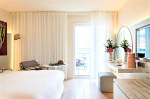 a hotel room with a bed and a balcony at Hotel Croisette Beach Cannes - Mgallery in Cannes