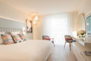 a white bedroom with a bed and a window at Hotel Croisette Beach Cannes - Mgallery in Cannes