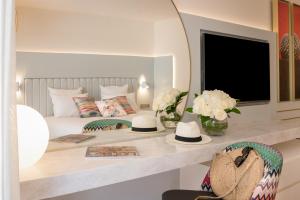 a bedroom with a bed and a table with hats on it at Hotel Croisette Beach Cannes - Mgallery in Cannes