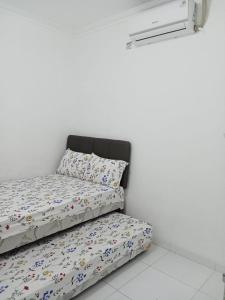 Posto letto in camera con parete bianca di homestay lima kamar tidur purwokerto a Purwokerto